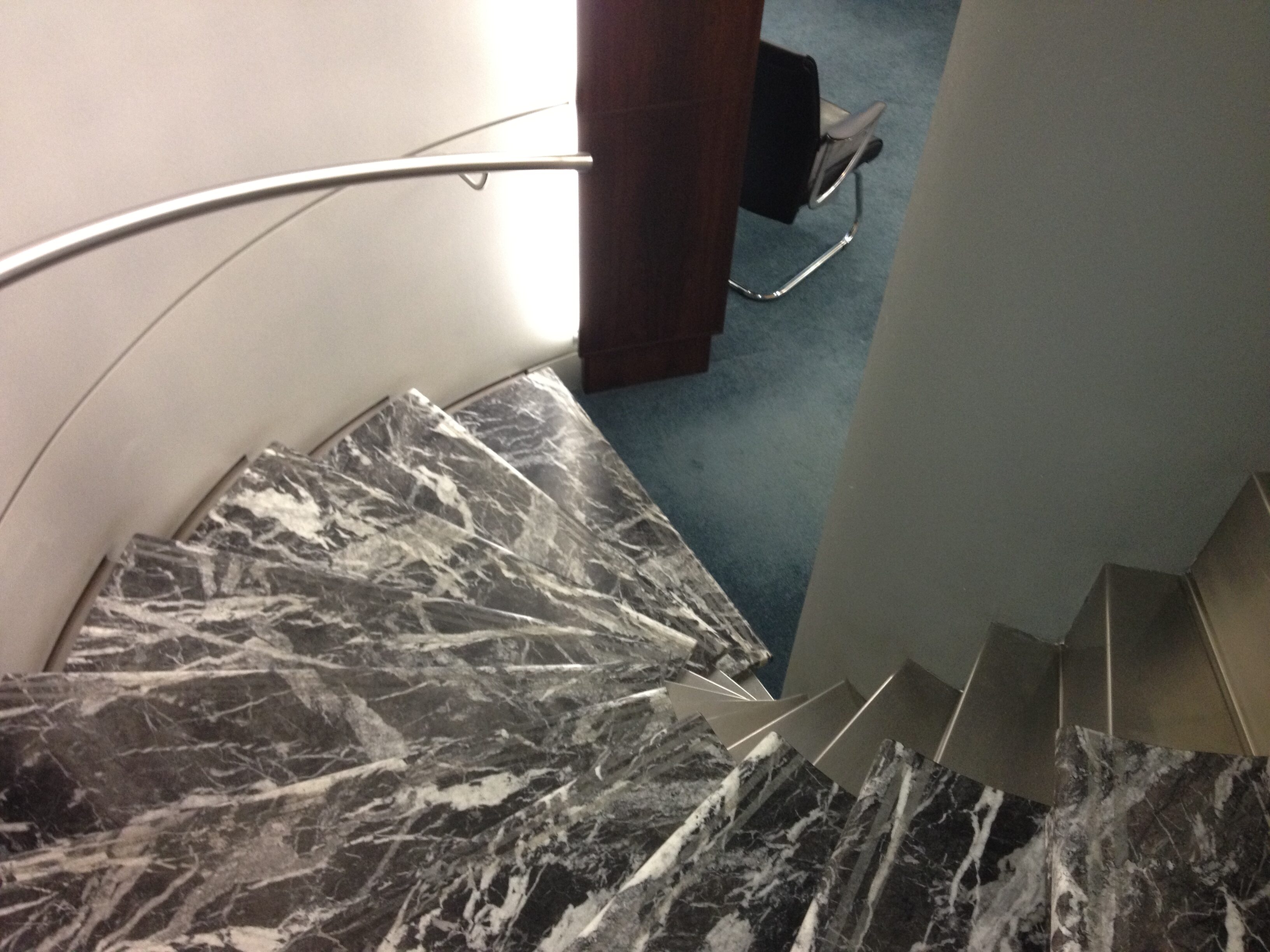 Custom stainless steel handrail mounted to wall for marble staircase - Elliott Engineering